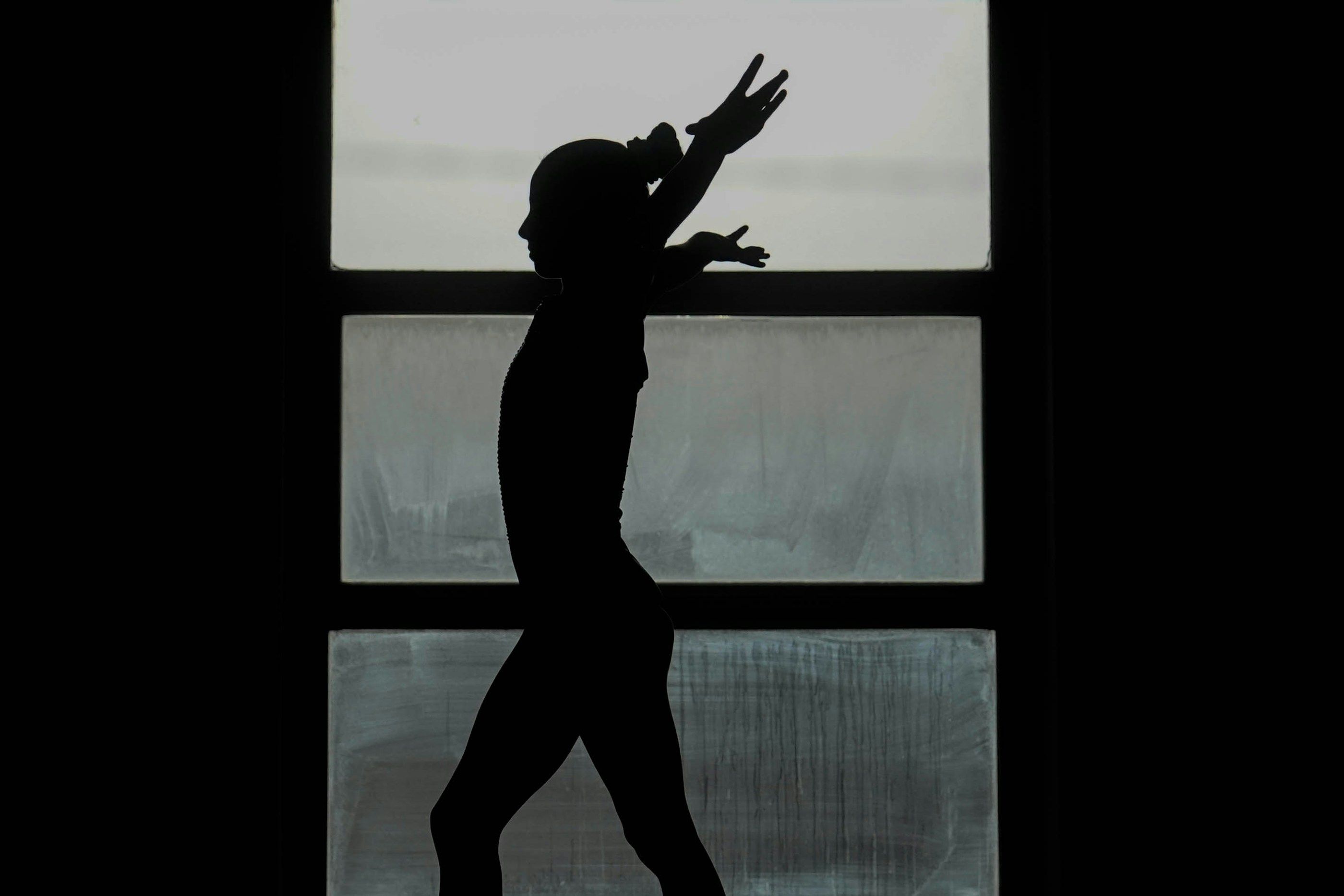 A dancer rehearsing against a window